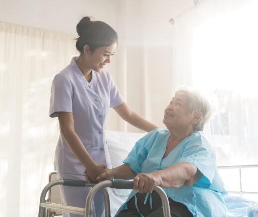 Asian nurse supporting elderly patient woman in using walker