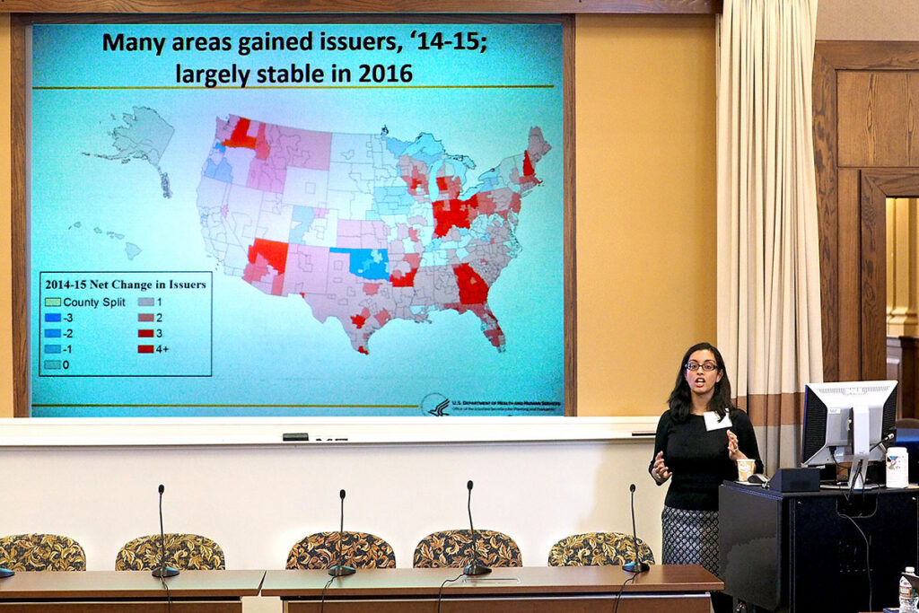 Penn's Aditi Sen, PhD at the podium with a map detailing patterns of health insurance across the country