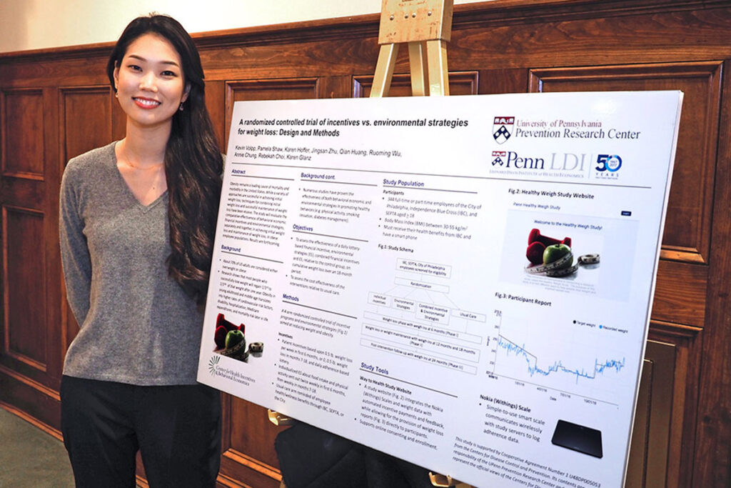 Rebekah Choi, MPH, with the poster of her team's randomized controlled trial of designs and methods for studies of incentives vs. environmental strategies for weight loss