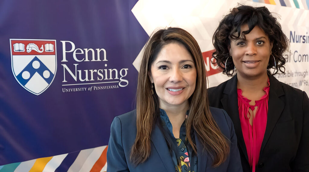 Penn Nursing School professors Adriana Perez and Margo Carthon in front of Penn Nursing banner.