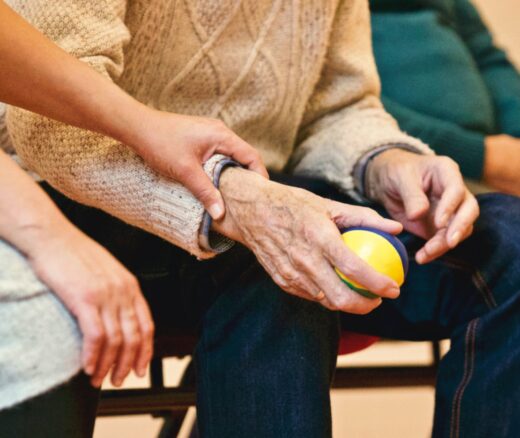 An older person holding a small ball