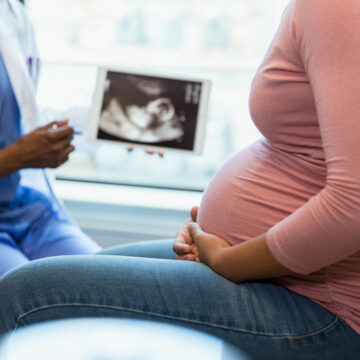 A pregnant person looking at a sonogram with their doctor.